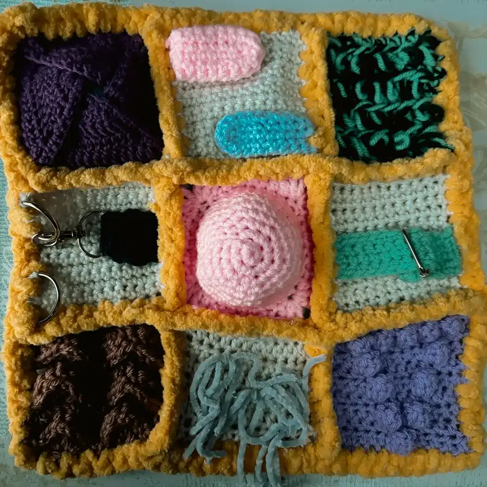 Close-up of a crocheted dementia fidget blanket with textured sensory sections.