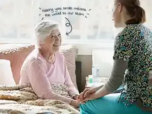 Elderly woman smiling while receiving compassionate home care support from a caregiver, showing warmth and reassurance in a comfortable home setting