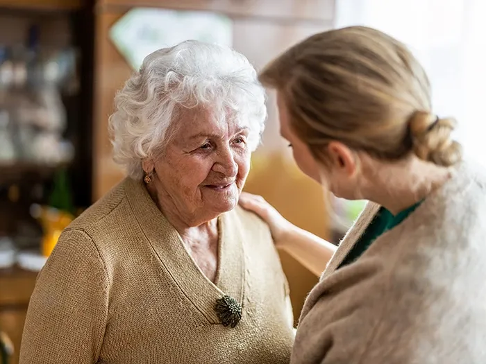 Elderly woman and homecarer together and smiling, highlighting companionship and emotional support for those coping with dementia.