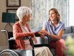 Carer assisting elderly woman with mobility support at home following hospital discharge