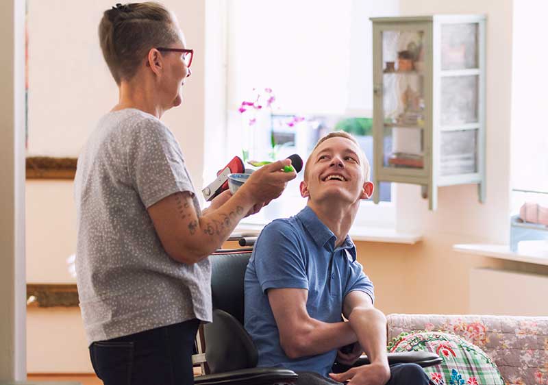 carer helping gentleman in wheelchair