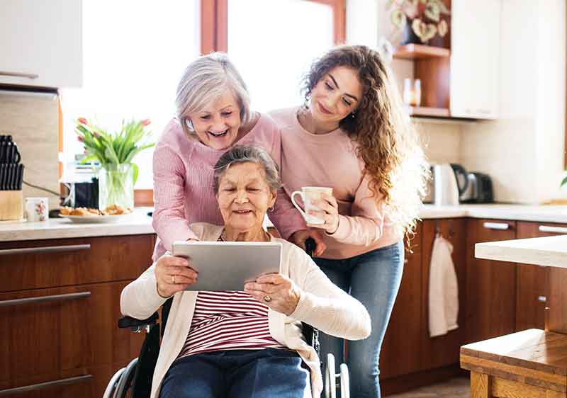 carer's showing lady how to use tablet to prevent social isolation