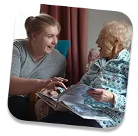 Trusted elderly caregiver laughing with client at home