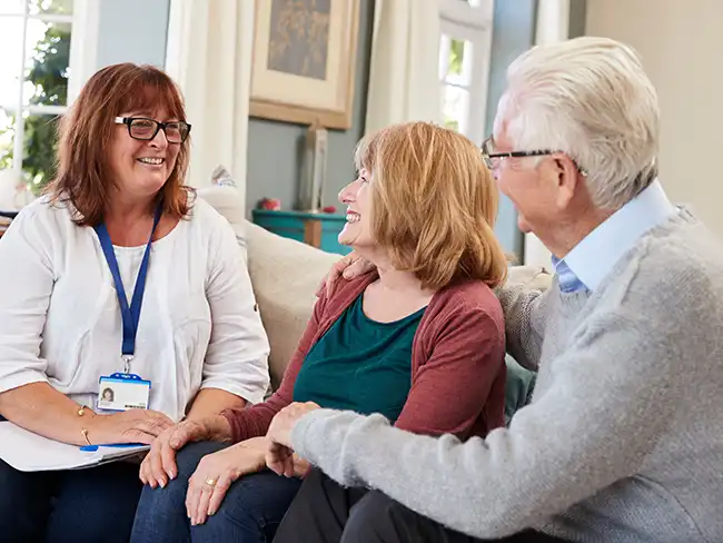 Carer providing hospital discharge advice and guidance to older couple at home