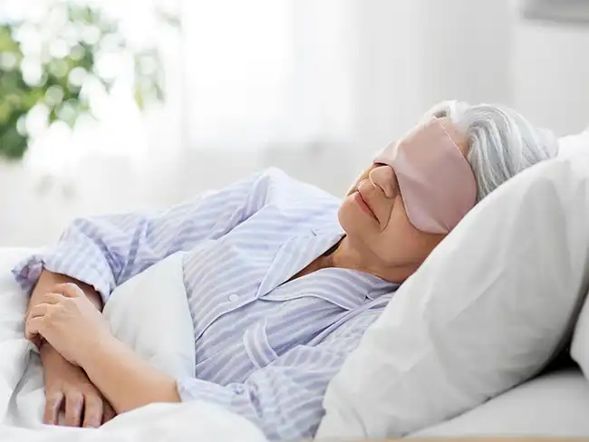 Elderly woman resting peacefully with an eye mask on — showing comfort and calm despite Alzheimer’s disease sleep problems.