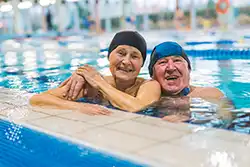 Happy senior couple enjoying swimming as part of preventative care exercise.
