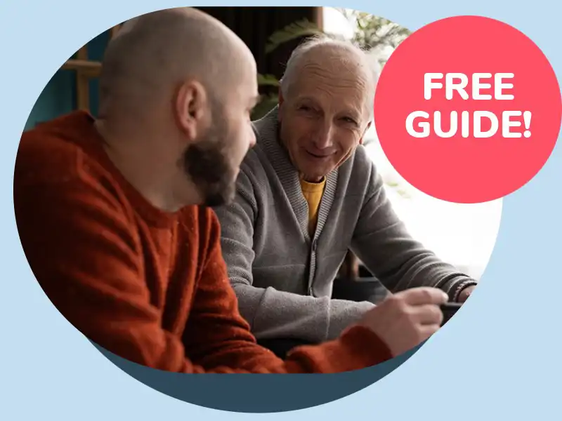 An older man talking with a younger man in a warm indoor setting, discussing winter preparations featured in the Winter Home Safety Checklist.