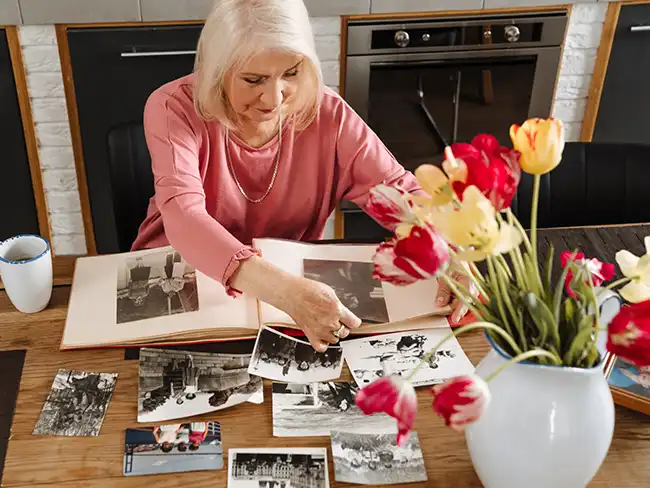 woman looking through a memory book and photos, symbolising Christmas gift ideas for older loved ones that celebrate personal memories.