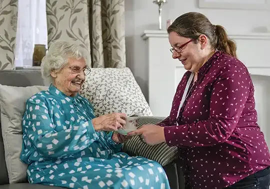 home care assistant giving cup of tea to client