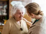Elderly woman and homecarer together and smiling, highlighting companionship and emotional support for those coping with dementia.