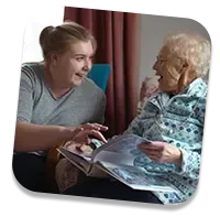 Trusted elderly caregiver laughing with client at home