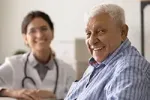 Smiling elderly man with a doctor during a preventative care health check.
