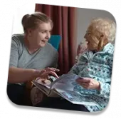 Trusted elderly caregiver laughing with client at home
