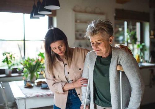 carer helping lady through her kitchen
